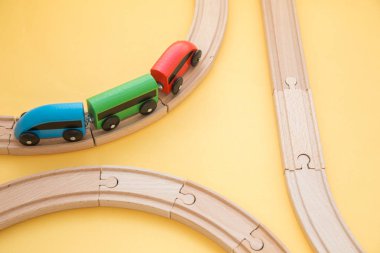 Çocuk oyuncakları sarı arka planda, oyuncak ahşap demiryolu ve tren. Üst Manzara. Flatlay. Metin için alanı kopyala