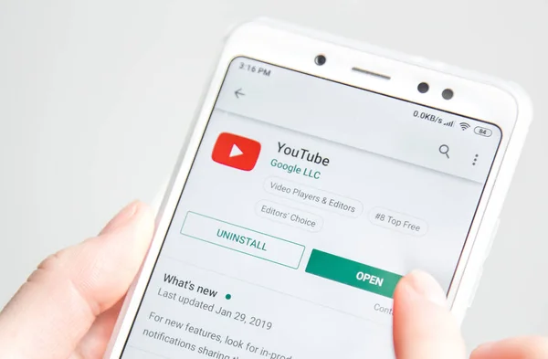 Ufa, Rusia enero 30, 2019: La mujer tiene en la mano un teléfono móvil e instala la aplicación youtubeapplication — Foto de Stock