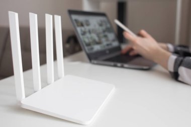 Kız ofiste beyaz Wi Fi yönlendirici yakın elinde telefon ile Laptop çalışır. Çok