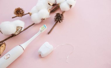 sabah dişleri ve yüz bakımı. pamuk çiçek, elektrikli ultrasonik diş fırçası ve Floss. üst görünüm düz pembe arka planda yatıyordu