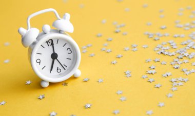 Beyaz masa saati, sarı arka planda alarm, üst görünüm. Günaydın. Minimalizm, düzlük