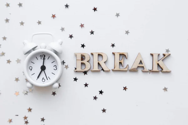 White table clock, alarm on white background, top view. Good morning. Minimalism, flatlay