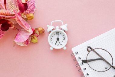 Beyaz masa saati, parlak arka planda çalar saat, üst görünüm. Ofiste iş yerinde mola. Kağıt, düzlük