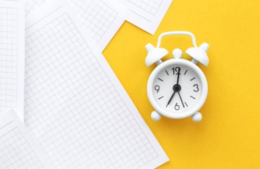 Beyaz masa saati, parlak arka planda çalar saat, üst görünüm. Ofiste iş yerinde mola. Kağıt