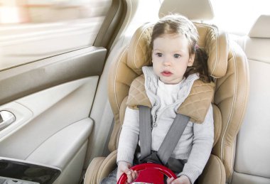 Bebek Oto Koltuğu çocuk. ISOFIX sıkma. aydınlık bir salonda bej araba koltuğu. Arabada koruma.