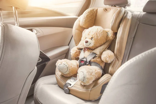 Παιδικό αμάξι. Ένα μπεζ αρκουδάκι είναι δεμένο με ζώνες ασφαλείας σε ένα κάθισμα αυτοκινήτου. Ταξιδέψτε με αυτοκίνητο — Φωτογραφία Αρχείου