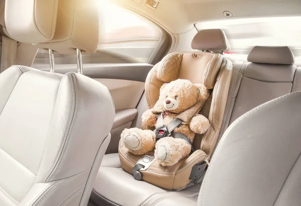 Bambino seggiolino auto. Un orsacchiotto beige è fissato con le cinture di sicurezza in un seggiolino auto. Viaggiare in auto — Foto Stock