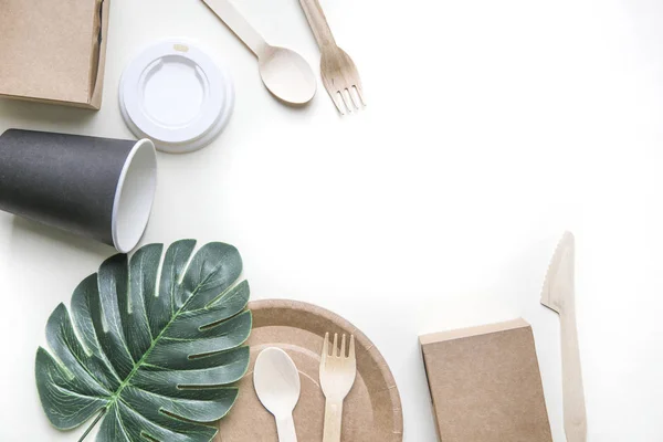 Екологічно чистий одноразовий посуд з паперу на білому мармуровому фоні. Загорнуті ложки, виделка, ножі, тарілка з паперовими чашками. концепція переробки — стокове фото