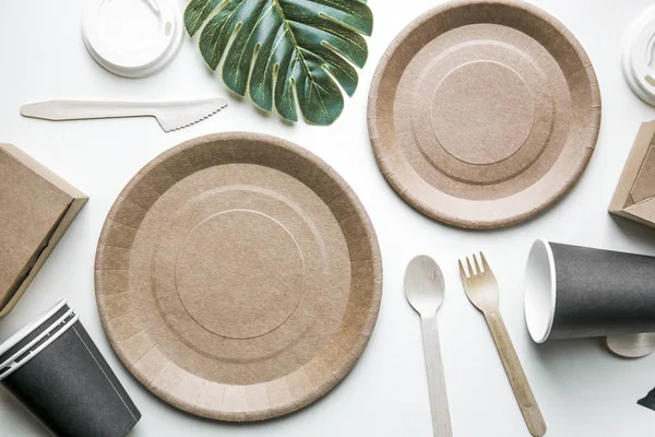 Plats jetables respectueux de l'environnement fait du papier sur fond de marbre blanc. Cuillères, fourchette, couteaux, assiette avec des tasses en papier. concept de recyclage — Photo