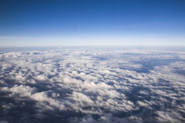 Öğleden sonra beyaz bulutlar ile mavi gökyüzü. uçağın aydınlatıcısından görünüm