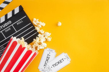 Sinema parti konsepti. film biletleri, clapperboard, pop mısır ve sarı bir arka plan 3d gözlük. Düz yatıyordu