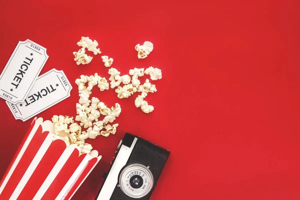 Cinema party concept. movie tickets, clapperboard, pop corn and 3d glasses in a red background. Flat lay