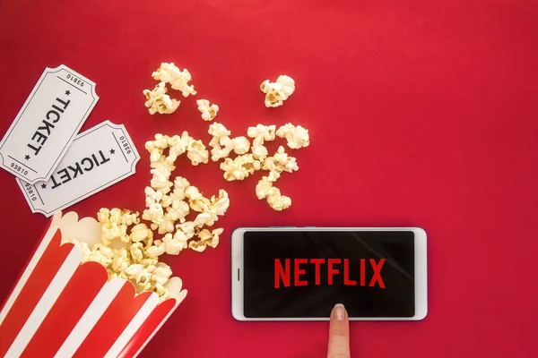 Ufa, Rusia - 7 de julio de 2019: Mesa con botella de palomitas de maíz y logotipo de Netflix en el teléfono inteligente. Netflix es un proveedor global de transmisión de películas y series de televisión . —  Fotos de Stock