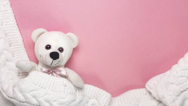pembe bir arka plan üzerinde kapakları altında küçük beyaz oyuncak ayı. Bekleyen kız, bebek partisi