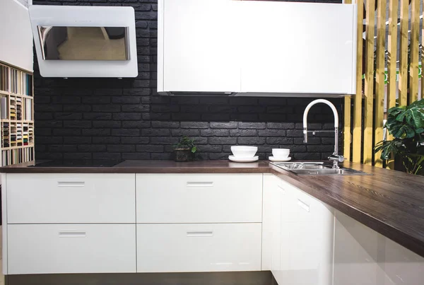 Interior de la cocina moderna con paredes de ladrillo negro, encimeras de madera con un fregadero incorporado y una cocina . — Foto de Stock