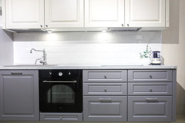 Interior de la cocina moderna con paredes de ladrillo blanco, encimeras de madera con un fregadero incorporado y una cocina . — Foto de Stock