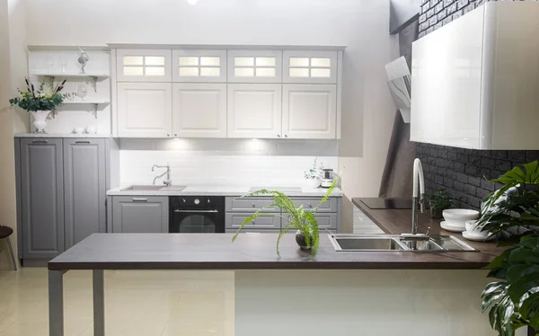 Interior de la cocina moderna con paredes de ladrillo blanco, encimeras de madera con un fregadero incorporado y una cocina . — Foto de Stock