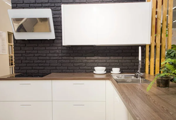 Interior de la cocina moderna con paredes de ladrillo negro, encimeras de madera con un fregadero incorporado y una cocina . — Foto de Stock