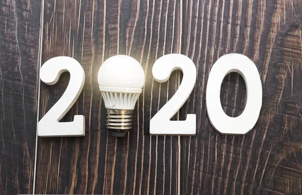 new idea 2020. Light bulb and numbers on a wooden background