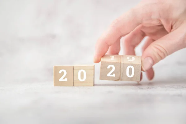 women hands hold wooden cubes 2020. new goals for next year.