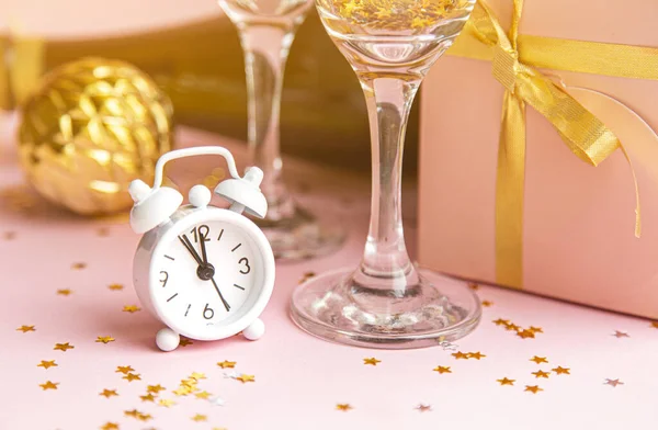 Composición navideña sobre fondo rosa pastel. Vasos con champán, confeti y reloj. Nochebuena 2020 . — Foto de Stock
