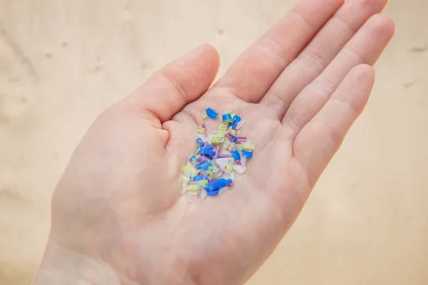 Plajdaki bir adamın elinde mikroplastik. Çevre kirliliği ve su mikro plastiği. — Stok fotoğraf