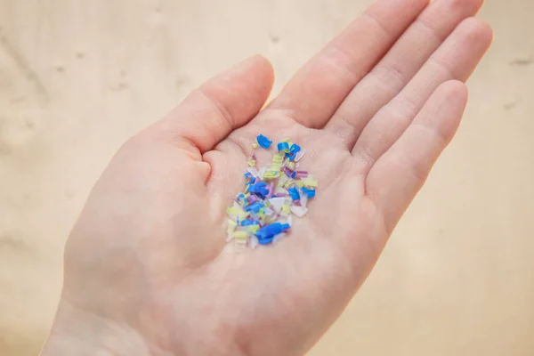 Plajdaki bir adamın elinde mikroplastik. Çevre kirliliği ve su mikro plastiği.