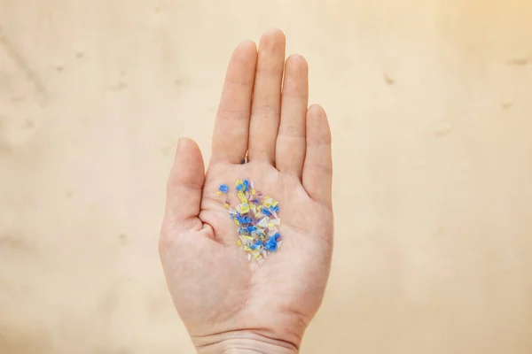 Plajdaki bir adamın elinde mikroplastik. Çevre kirliliği ve su mikro plastiği.