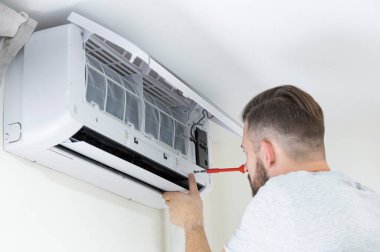 Erkek teknisyen içeride klimayı temizliyor. Klimayı temizleyen teknisyen servisi.