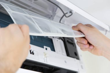 Erkek teknisyen içeride klimayı temizliyor. Klimayı temizleyen teknisyen servisi, filtre değişikliği.