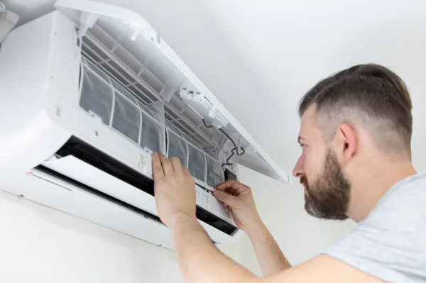 Male technician cleaning air conditioner indoors. technician service cleaning the conditioner.