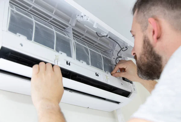 Male technician cleaning air conditioner indoors. technician service cleaning the conditioner, filter change.