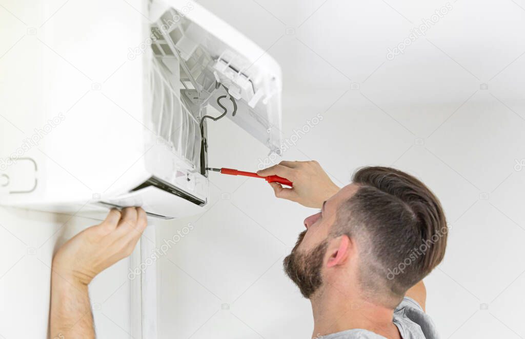 Male technician cleaning air conditioner indoors. technician service cleaning the conditioner.