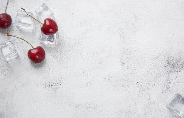 Üst manzara kiraz ve buz küpü gri beton arka planda. Yaz süsü konsepti