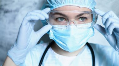 Coronavirus salgını sırasında maskeli bir hemşire, ve güvenlik gözlüğü, eldivenler. Kapat.