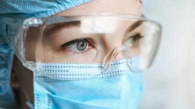 Coronavirus salgını sırasında maskeli bir hemşire, ve güvenlik gözlüğü, eldivenler. Kapat.