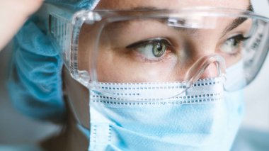 Coronavirus salgını sırasında maskeli bir hemşire, ve güvenlik gözlüğü, eldivenler. Kapat.