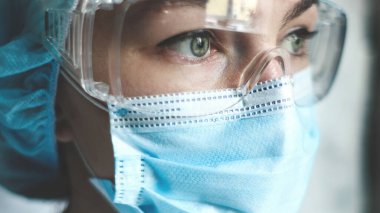 Coronavirus salgını sırasında maskeli bir hemşire, ve güvenlik gözlüğü, eldivenler. Kapat.