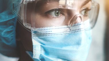 Coronavirus salgını sırasında maskeli bir hemşire, ve güvenlik gözlüğü, eldivenler. Kapat.
