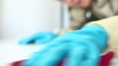 Temizlik servisi. Eldivenli genç bir kadın evdeki paçavra, dezenfeksiyon ve ev temizliği ile pencerenin kenarındaki tozu siliyor.