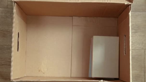 Close-up of a cardboard box for relocation. woman puts things up. accelerated shooting. timelapse, hyperlapse — Stock Video