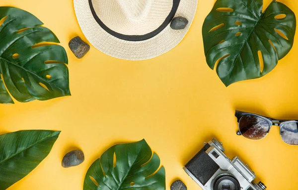 Cappello di paglia e occhiali da sole su uno sfondo di foglie di palma. Layout creativo tropicale estate viaggio vista dall'alto. Piatto. Concetto di vacanza. — Foto Stock
