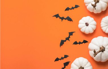 Cadılar Bayramınız kutlu olsun. Turuncu kağıdın üzerinde düz bir kompozisyon vardı. Beyaz balkabakları ve yarasalar.