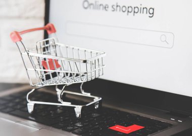 İnternetten alışveriş. Laptop klavyesinde alışveriş arabası. Malların evinize ve ofisinize getirilmesi ve teslimatı.