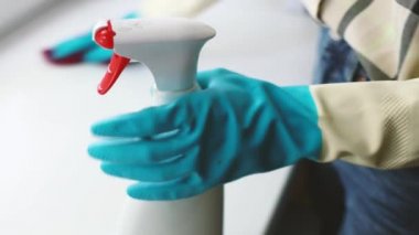 Temizlik servisi. Eldivenli genç bir kadın evdeki dezenfektan köpüğü, dezenfeksiyon ve ev temizliği ile pencere pervazındaki tozu siliyor.