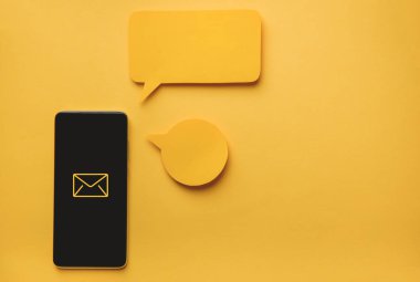 Akıllı telefon ve İleti baloncukları sarı arkaplanda sohbet kağıtları