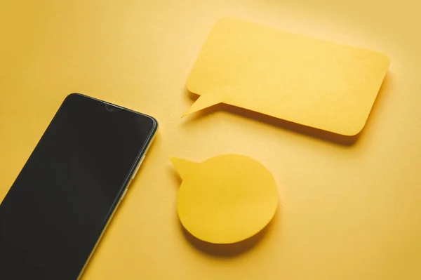 Smartphone y mensaje burbujas de chat de papel sobre fondo amarillo — Foto de Stock