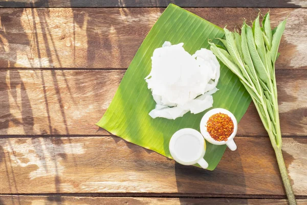 The food menu of white konjac noodles is in a cup, decorated on a banana leaf on a wooden table and surrounded by ingredients and leaves. It contains glucomannan extract, making it healthy and diet