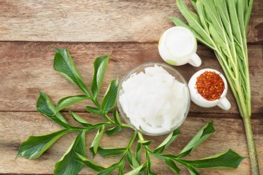 Beyaz Konjac eriştelerinin yemek menüsü bir fincanda, eski bir ahşap masaya dekore edilmiş ve malzemeler ve yeşil yapraklarla çevrili. Glukomannan özütü içeriyor, sağlıklı ve diyet yapıyor.