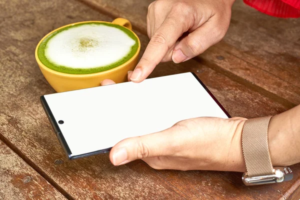 El masada bir cep telefonu ve yeşil çay bir bardak ile oynuyor         